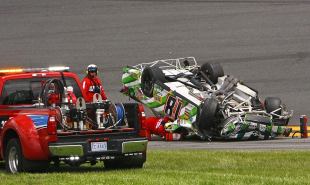 Track officials check on the condition of Kyle Busch, still in the car, after he flipped over in a ...