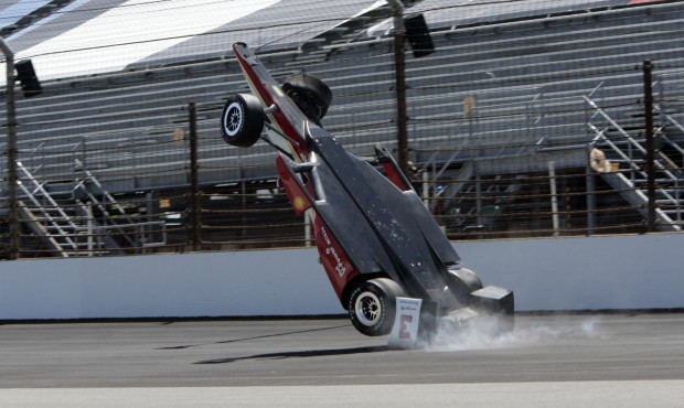 The car driven by Helio Castroneves, of Brazil, flips after hitting the wall in the first turn duri...