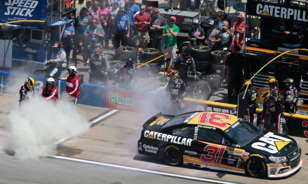 Emergency personnel put out a fire near a crew member for Ryan Newman (31) in the pit area during t...