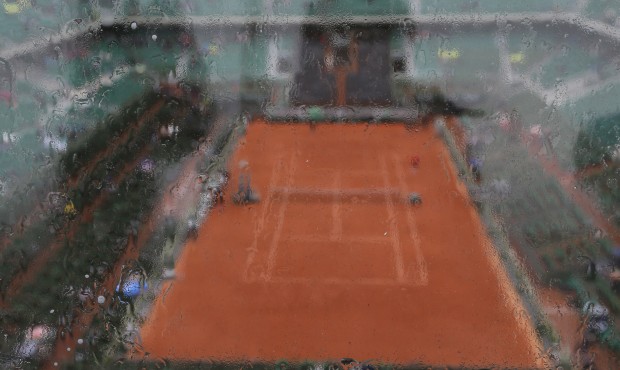 Raindrops trickle down a glass security barrier as the fourth round match between France’s Al...