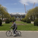 
              A cyclist passes by the USTA Billie Jean King Tennis Center as construction on a roof over Arthur Ashe Stadium continues, Friday, May 1, 2015, in New York. While Wimbledon and the Australian Open already put retractable roofs over their main stadiums, players and fans at the U.S. Open won’t be able to enjoy the final result until the 2016 tournament. (AP Photo/Julie Jacobson)
            