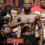 
              Floyd Mayweather Jr. poses on the scale as Manny Pacquiao's trainer Freddie Roach, second from lower left, closely watches, during his weigh-in on Friday, May 1, 2015 in Las Vegas. The world weltherweight title fight between Mayweather Jr. and Manny Pacquiao is scheduled for May 2. (AP Photo/Chris Carlson)
            