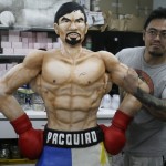 
              Zach Yonzon, owner of The Bunny Baker cafe, poses with the life-sized cake of Filipino boxer Manny Pacquiao Saturday, May 2, 2015 at his bakeshop at suburban Quezon city, northeast of Manila, Philippines. Yonzon who says he was bored with making traditional cakes sculpted the one-of-a-kind life-sized cake in the image of Pacquiao to mark the Filipino champion’s megabout with American Floyd Mayweather. Yonzon, says his wife Aila and six of his staff helped finish the 167-centimeter (66-inch) chocolate cake of Pacquiao with arms akimbo on Saturday after working 24 hours at the cafe. (AP Photo/Bullit Marquez)
            