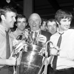
              FILE - In this May 30, 1968 file photo, Pat Crerand, left, and George Best, right, of Manchester United hold the European Cup with their manager Matt Busby, at Euston Station, in London, the day after Manchester United beat Portugal's Benfica 4-1 at Wembley, in London. Ten years after the Munich air disaster, which killed 23 people, including eight Manchester United players, Busby led his team to European Cup glory. His rebuilt team was full of attacking flair, notably in the form of the young Northern Irishman George Best and England’s Bobby Charlton, who together scored three of United’s goals. (AP Photo/Victor Boyton, File)
            