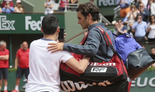 A boy who climbed down from the stands takes a selfie with Switzerland’s Roger Federer in the...