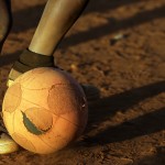 
              A young boy controls the ball while playing soccer with others,  on a dusty field in Thokoza township east of Johannesburg, South Africa, Thursday, May 28, 2015. The image of South Africa’s 2010 World Cup has been shattered by allegations that its bid over a decade ago was involved in bribes of more than $10 million to secure FIFA votes - possibly with the knowledge or involvement of the South African government.  (AP Photo/Themba Hadebe)
            