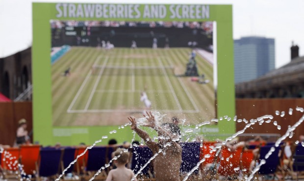 Six-year-old Harvey enjoys playing with water as the Wimbledon Tennis Championships are seen on a h...