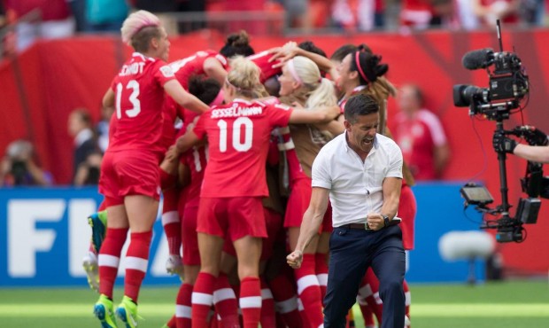 Canada coach John Herdman, right, celebrates as Josee Belanger, back, is mobbed by her teammates af...