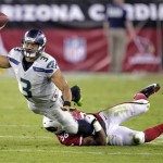 Seattle Seahawks quarterback Russell Wilson (3) gets a pass off as Arizona Cardinals inside linebacker Karlos Dansby (56) brings him down during the second half of an NFL football game, Thursday, Oct. 17, 2013, in Glendale, Ariz. (AP Photo/Rick Scuteri)