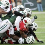 Arizona Cardinals running back Beanie Wells, center in red, is tackled by a host of New York Jets players during the first half of an NFL football game, Sunday, Dec. 2, 2012, in East Rutherford, N.J. (AP Photo/Bill Kostroun)