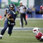Seattle Seahawks quarterback Russell Wilson, left, makes a long run against the Arizona Cardinals in the first half of an NFL football game, Sunday, Nov. 23, 2014, in Seattle, but the play was called back due to a holding penalty against the Seahawks. (AP Photo/Stephen Brashear)