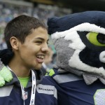 Nate Hatch, a student who was injured in an October 2014 shooting at Marysville-Pilchuck high school in Marysville, Wash., stands with "Blitz" the Seattle Seahawks mascot during pre-game activities before an NFL football game between the Seattle Seahawks and the Arizona Cardinals, Sunday, Nov. 23, 2014, in Seattle. (AP Photo/Elaine Thompson)