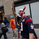 Houston Texans fan Ryan Dove, of Houston, Texas, waves as he is taunted by fans waiting in line outside Radio City Music Hall before the first round of the NFL football draft, Thursday, May 8, 2014, in New York. (AP Photo/Jason DeCrow)