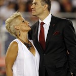 Former Arizona Cardinals quarterback Kurt Warner and his wife, Brenda Warner, left, stand on the field as Warner is inducted into the Cardinals' ring of honor at halftime during an NFL football game against the San Diego Chargers, Monday, Sept. 8, 2014, in Glendale, Ariz. (AP Photo/Rick Scuteri)