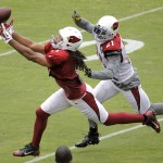 Arizona Cardinals' Larry Fitzgerald, left, reaches for the pass as Patrick Peterson defends during football camp practice, Monday, Aug. 18, 2014, in Glendale, Ariz. (AP Photo/Matt York)