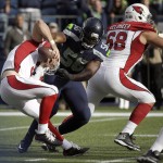 Arizona Cardinals quarterback Drew Stanton, left, tries to escape a tackle by Seattle Seahawks defensive end Cliff Avril as Cardinals' Jared Veldheer, right, blocks in the first half of an NFL football game, Sunday, Nov. 23, 2014, in Seattle. (AP Photo/Elaine Thompson)