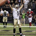 New Orleans Saints quarterback Drew Brees (9) celebrates after rushing for a touchdown in the second half of an NFL football game against the Arizona Cardinals in New Orleans, Sunday, Sept. 22, 2013. Saints wide receiver Lance Moore (16) and Cardinals cornerback Jerraud Powers (25) look on. (AP Photo/Bill Haber)