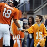 A youngster reaches to shake the hand of Denver Broncos quarterback Peyton Manning (18) before a preseason NFL football game against the Arizona Cardinals, Thursday, Aug. 29, 2013, in Denver. (AP Photo/Jack Dempsey)