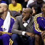 An injured Los Angeles Lakers' Kobe Bryant, middle, watches from the team bench as he is flanked by teammates Metta World Peace, right, and Robert Sacre in the second half of an NBA basketball game against the Phoenix Suns on Monday, March 18, 2013, in Phoenix. The Suns defeated the Lakers 99-76. (AP Photo/Ross D. Franklin)