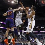 New Orleans Pelicans point guard Jrue Holiday (11) goes to the basket between power forward Anthony Davis (23) and Phoenix Suns power forward Miles Plumlee (22) in the first half of an NBA basketball game in New Orleans, Tuesday, Nov. 5, 2013. (AP Photo/Gerald Herbert)