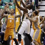 Utah Jazz's Paul Millsap, center, reaches for a rebound as Phoenix Suns' Michael Beasley (0) and Shannon Brown, right, watch in the second quarter during an NBA basketball game, Wednesday, March 27, 2013, in Salt Lake City. (AP Photo/Rick Bowmer)