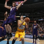 Phoenix Suns guard Goran Dragic, left, of Slovenia, flies over Denver Nuggets guard Evan Fournier, of France, as he goes up for a shot while Suns forward Marcus Morris, back comes in to cover in the third quarter of the Suns' 103-99 victory in an NBA basketball game in Denver on Friday, Dec. 20, 2013. (AP Photo/David Zalubowski)