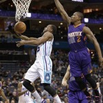 Charlotte Hornets' Kemba Walker, left, drives past Phoenix Suns' Eric Bledsoe, right, during the first half of an NBA basketball game in Charlotte, N.C., Wednesday, Dec. 17, 2014. (AP Photo/Chuck Burton)