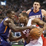 Toronto Raptors' Kyle Lowry, center, drives the ball to the basket between Phoenix Suns Eric Bledsoe, left, and Alex Len during the first half of an NBA basketball game in Toronto on Monday, Nov. 24, 2014. (AP Photo/The Canadian Press, Darren Calabrese)