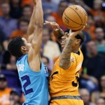 Phoenix Suns guard Isaiah Thomas (3) passes around Charlotte Hornets guard Brian Roberts during the first half of an NBA basketball game, Friday, Nov. 14, 2014, in Phoenix. (AP Photo/Matt York)