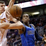 Dallas Mavericks' Rajon Rondo, right, tries to get off a shot as Phoenix Suns' Alex Len, left, of the Ukraine, and Goran Dragic, second from left, of Slovenia, defend during the first half of an NBA basketball game Tuesday, Dec. 23, 2014, in Phoenix. (AP Photo/Ross D. Franklin)
