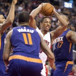 Toronto Raptors' DeMar DeRozan, second from right, drives to the basket between Phoenix Suns, from left, Marcus Morris, Markieff Morris, and P.J. Tucker during the first half of an NBA basketball game in Toronto on Monday, Nov. 24, 2014. (AP Photo/The Canadian Press, Darren Calabrese)