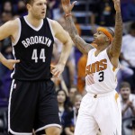 Phoenix Suns' Isaiah Thomas (3) celebrates as Brooklyn Nets' Bojan Bogdanovic (44), of Croatia, walks up the court during the second half of an NBA basketball game Wednesday, Nov. 12, 2014, in Phoenix. The Suns defeated the Nets 112-104. (AP Photo/Ross D. Franklin)