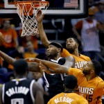 Sacramento Kings center DeMarcus Cousins (15) shoots as Phoenix Suns' Marcus Morris (15) and Markieff Morris, rear, defend during the first half of an NBA basketball game, Friday, Nov. 7, 2014, in Phoenix. The Kings won 114-112 in double overtime. (AP Photo/Matt York)