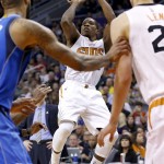 Phoenix Suns' Eric Bledsoe, middle, gets a shot off as Suns' Alex Len, right, of the Ukraine, and Dallas Mavericks' Tyson Chandler, left, look on during the second half of an NBA basketball game Tuesday, Dec. 23, 2014, in Phoenix. The Suns won 124-115. (AP Photo/Ross D. Franklin)
