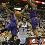 Minnesota Timberwolves guard Ricky Rubio (9), of Spain, falls as he splits the defense of Phoenix Suns guard Eric Bledsoe, left, and forward P.J. Tucker, right, during the fourth quarter of an NBA basketball game in Minneapolis, Sunday, March 23, 2014. The Suns won 127-120. (AP Photo/Ann Heisenfelt)