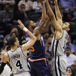 Phoenix Suns forward Marcus Morris, center, shoots against San Antonio Spurs' Jeff Ayres, right, and Danny Green, during the first half of an NBA basketball game on Friday, April 11, 2014, in San Antonio. (AP Photo/Darren Abate)
