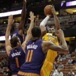 Los Angeles Lakers' Kobe Bryant, top right, puts up a shot as he is defended by Phoenix Suns' Eric Bledsoe, top left, Goran Dragic, left, of Slovenia, and Markieff Morris during the first half of a preseason NBA basketball game on Tuesday, Oct. 21, 2014, in Anaheim, Calif. (AP Photo/Jae C. Hong)