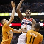  Washington Wizards' Kevin Seraphin (13), of France, gets off a shot but knocks over Phoenix Suns' Markieff Morris (11) for a charging foul as Suns' Alex Len, left, of the Ukraine, defends during the first half of an NBA basketball game, Friday, Jan. 24, 2014, in Phoenix. (AP Photo/Ross D. Franklin)