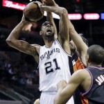 San Antonio Spurs' Tim Duncan (21) is fouled by Phoenix Suns' Luis Scola, rear, of Argentina, during the first half of an NBA basketball game, Wednesday, Feb. 27, 2013, in San Antonio. Suns' Wesley Johnson, right, also defends on the play. (AP Photo/Eric Gay)