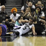 San Antonio Spurs' Marco Belinelli, of Italy, slides out of bounds after colliding with Phoenix Suns' Archie Goodwin, left, during the second half of an NBA preseason basketball game, Sunday, Oct. 13, 2013, in San Antonio. Phoenix won 106-99. (AP Photo/Darren Abate)