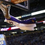 Phoenix Suns' Marcus Morris holds onto the rim after dunking as Denver Nuggets' Corey Brewer looks away during the second half of an NBA basketball game, Monday, March 11, 2013, in Phoenix. (AP Photo/Matt York)