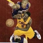 Cleveland Cavaliers' Luol Deng (9), from Sudan, puts up a shot against Phoenix Suns' P.J. Tucker, top and Miles Plumlee (22) in the first half of an NBA basketball game, Sunday, Jan. 26, 2014, in Cleveland. (AP Photo/Mark Duncan)