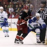Phoenix Coyotes' Radim Vrbata (17), of the Czech Republic, checks Vancouver Canucks' Zack Kassian (9) into the boards as linesman Steve Miller (89) tries to get out of the way and Canucks' Dan Hamhuis (2) looks on during the first period of an NHL hockey game on Tuesday, Nov. 5, 2013, in Glendale, Ariz. (AP Photo/Ross D. Franklin)