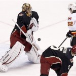 Phoenix Coyotes' Thomas Greiss, left, of Germany, makes a save on a shot by Calgary Flames' Paul Byron (32) as Coyotes' Connor Murphy (5) looks on during the third period of an NHL hockey game Tuesday, Jan. 7, 2014, in Glendale, Ariz. The Coyotes defeated the Flames 6-0. (AP Photo/Ross D. Franklin)