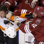 Phoenix Coyotes' Paul Bissonnette (12) connects with a punch, knocking off the helmet of Philadelphia Flyers' Jay Rosehill, left, as they fight during the second period of an NHL hockey game Saturday, Jan. 4, 2014, in Glendale, Ariz. (AP Photo/Ross D. Franklin)