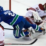 Vancouver Canucks' Kevin Bieksa, centre, scores the winning goal against Phoenix Coyotes' goalie Mike Smith, right, as Michael Stone watches during an NHL hockey game in Vancouver, British Columbia, on Sunday, Jan. 26, 2014. (AP Photo/The Canadian Press, Darryl Dyck)