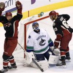 Phoenix Coyotes' David Moss, left, and Mike Ribeiro (63) celebrate a goal by teammate Shane Doan, as Vancouver Canucks' Roberto Luongo (1) kneels dejectedly on the ice during the second period of an NHL hockey game on Tuesday, Nov. 5, 2013, in Glendale, Ariz. (AP Photo/Ross D. Franklin)