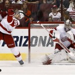 Detroit Red Wings' Jimmy Howard, right, makes a save as Red Wings' Niklas Kronwall (55), of Sweden, gets hit by Phoenix Coyotes' Chris Brown, left, in the first period of an NHL hockey game on Thursday, April 4, 2013, in Glendale, Ariz. (AP Photo/Ross D. Franklin)