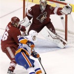 Phoenix Coyotes' Mike Smith (41) makes a glove save on a shot by New York Islanders' Eric Boulton, right, as Coyotes' Michael Stone, left, defends during the second period of an NHL hockey game Thursday, Dec. 12, 2013, in Glendale, Ariz. (AP Photo/Ross D. Franklin)