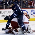 Winnipeg Jets' Michael Frolik (67) ends up on top of Phoenix Coyotes' goaltender Mike Smith (41) after a good scoring chance during second period NHL hockey action in Winnipeg, Canada, Monday, Jan. 13, 2014. (AP Photo/The Canadian Press, Trevor Hagan)